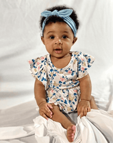 Baby girl is wearing a blue knotted headband for little girls from By Bella Boutique.